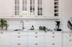 a kitchen with white cabinets and gold knobs on the cupboards is pictured in this image