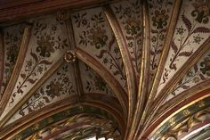 an ornately decorated ceiling with gold and red paint on the walls, in a building