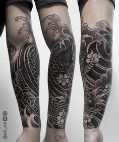 two people with black and white tattoos on their legs, one is holding a fish