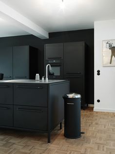 a kitchen with black cabinets and a stainless steel trash can next to the counter top