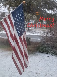 an american flag hanging in the snow with merry christmas written on it's side