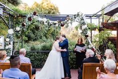 a bride and groom kiss as they stand in front of an outdoor ceremony