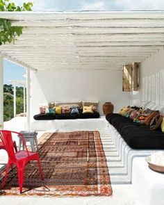 an outdoor living area with black and white couches, pillows and rugs on the floor