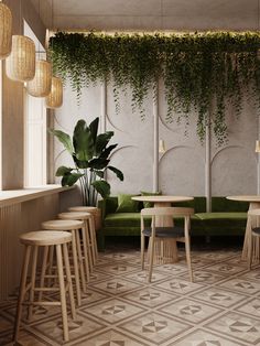 a green couch and some stools in a room with plants growing on the wall