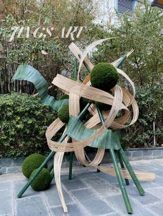 a sculpture made out of bamboo sticks and green balls on top of each other in front of a building