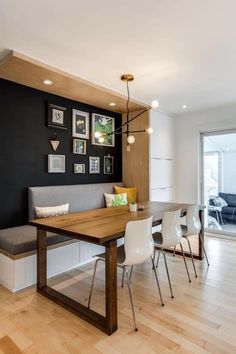 a dining room table with white chairs and pictures on the wall