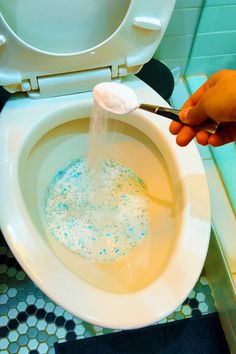 a person is using a plunger to flush a toilet with blue and white sprinkles