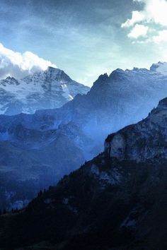 the mountains are covered in snow and clouds