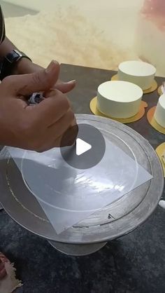 someone is decorating a cake with white frosting and yellow circles on the plate