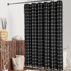 a black and white shower curtain hanging on a bathroom wall next to a wooden cabinet