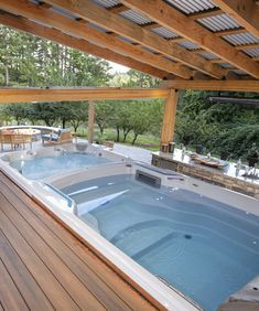 a large hot tub sitting on top of a wooden deck next to a table and chairs