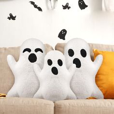 three white ghost pillows sitting on top of a couch