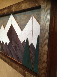 a wooden wall hanging with mountains and trees on it's sides in a wood frame