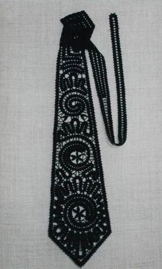 a black beaded neck tie laying on top of a white cloth covered tablecloth