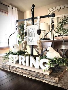 a sign that says spring on top of a wooden table with birds and greenery