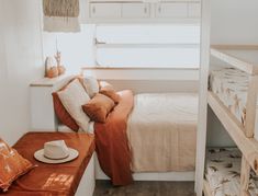 a bed sitting next to a window with pillows on top of it in a bedroom