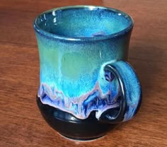 a blue and black cup sitting on top of a wooden table