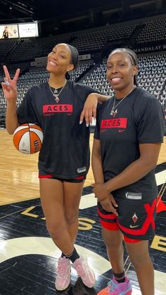 two women standing next to each other in front of a basketball ball on a court