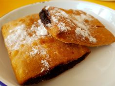 two pastries covered in powdered sugar on a white plate