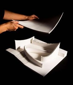 two hands are holding open white boxes on a black background, one is folded and the other is unwrapped