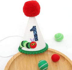 a birthday hat with the number one on it and balls around it, including a tennis ball