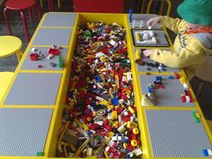 a child playing with legos at a table in a playroom filled with yellow chairs