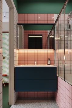 a bathroom with pink and green tiles on the walls, sink and shower stall area