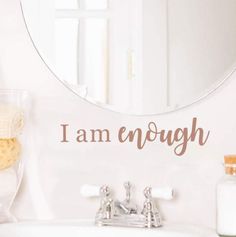 a bathroom sink with a mirror above it and the words i am enough written on the wall