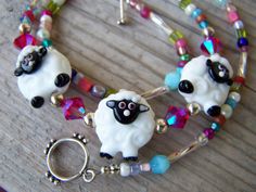 a necklace with two sheep on it and beads around the neck, sitting on a wooden surface