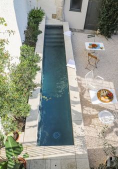 an aerial view of a small pool in the middle of a patio with tables and chairs around it