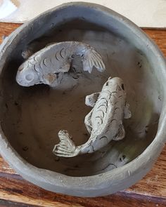 two fish in a bowl on a wooden table