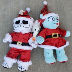 two stuffed animals dressed as santa claus and snowman are laying on the ground next to each other