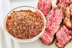 steak with seasoning in a bowl on a white plate next to other meats