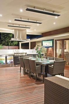 an outdoor dining area with wooden flooring and lights on the ceiling, surrounded by wicker furniture