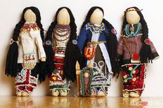 three wooden dolls are lined up against a white wall and one has long black hair