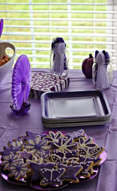 a table topped with purple and white decorated cookies