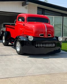 an old red truck parked in front of a garage