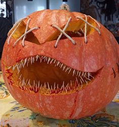 a carved pumpkin with sharp teeth and fangs on it's face, sitting on a table