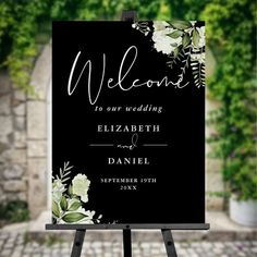 a black and white sign with flowers on it that says, welcome to our wedding