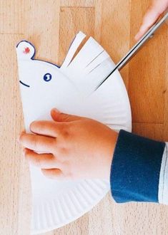 a person cutting paper with scissors on top of a white plate that is shaped like a unicorn