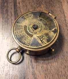 an antique brass pocket watch on a wooden table with keyring in the foreground