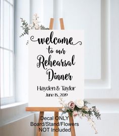 an easel with a sign that says welcome to our rehearsal dinner, and flowers on it