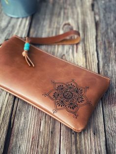 a brown leather wallet sitting on top of a wooden table next to a coffee cup