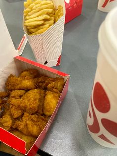 chicken nuggets and french fries are sitting on the table next to two cups of soda