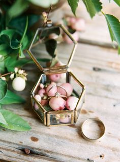 a wedding ring sitting on top of a wooden table next to flowers and greenery