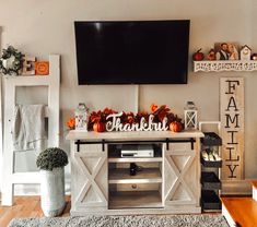 a living room decorated for thanksgiving with pumpkins and decorations on the tv stand in front of it