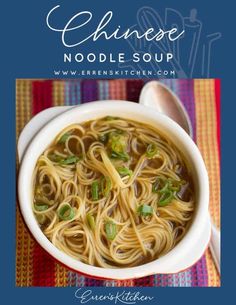 chinese noodle soup in a white bowl on a colorful table cloth with spoons