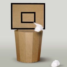 a cardboard box with a basketball hoop on top of it and a white ball in front of it