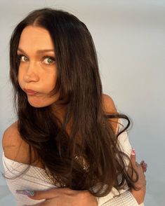 a woman with long brown hair is posing for the camera