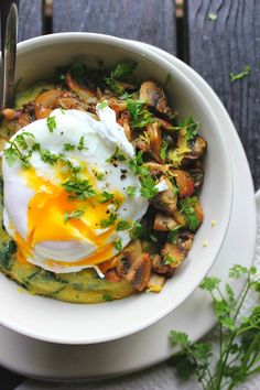 a white bowl filled with food on top of a wooden table next to a fork